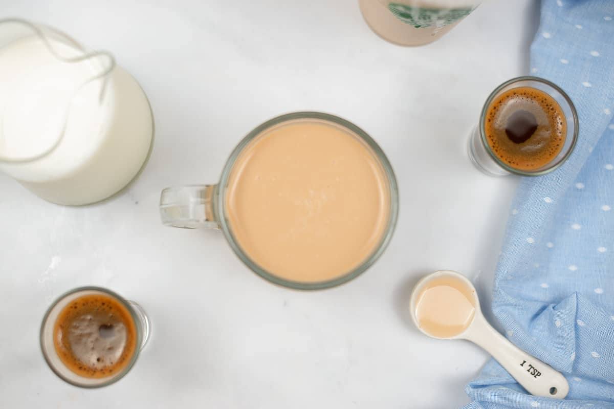 top view of a mug of copycat starbucks white chocolate mocha surrounded by milk, espresso shots, and white chocolate sauce