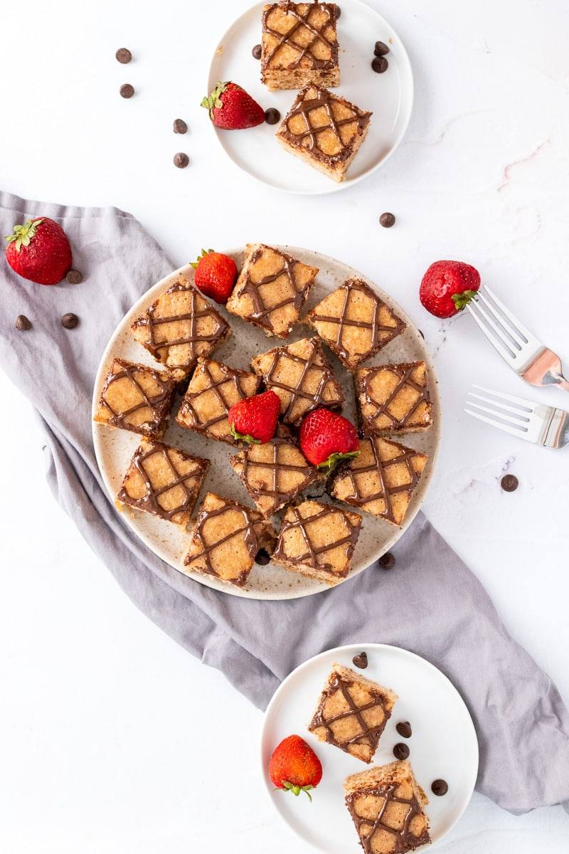 big plate of strawberry blondies being served, alongside a smaller smerving plate
