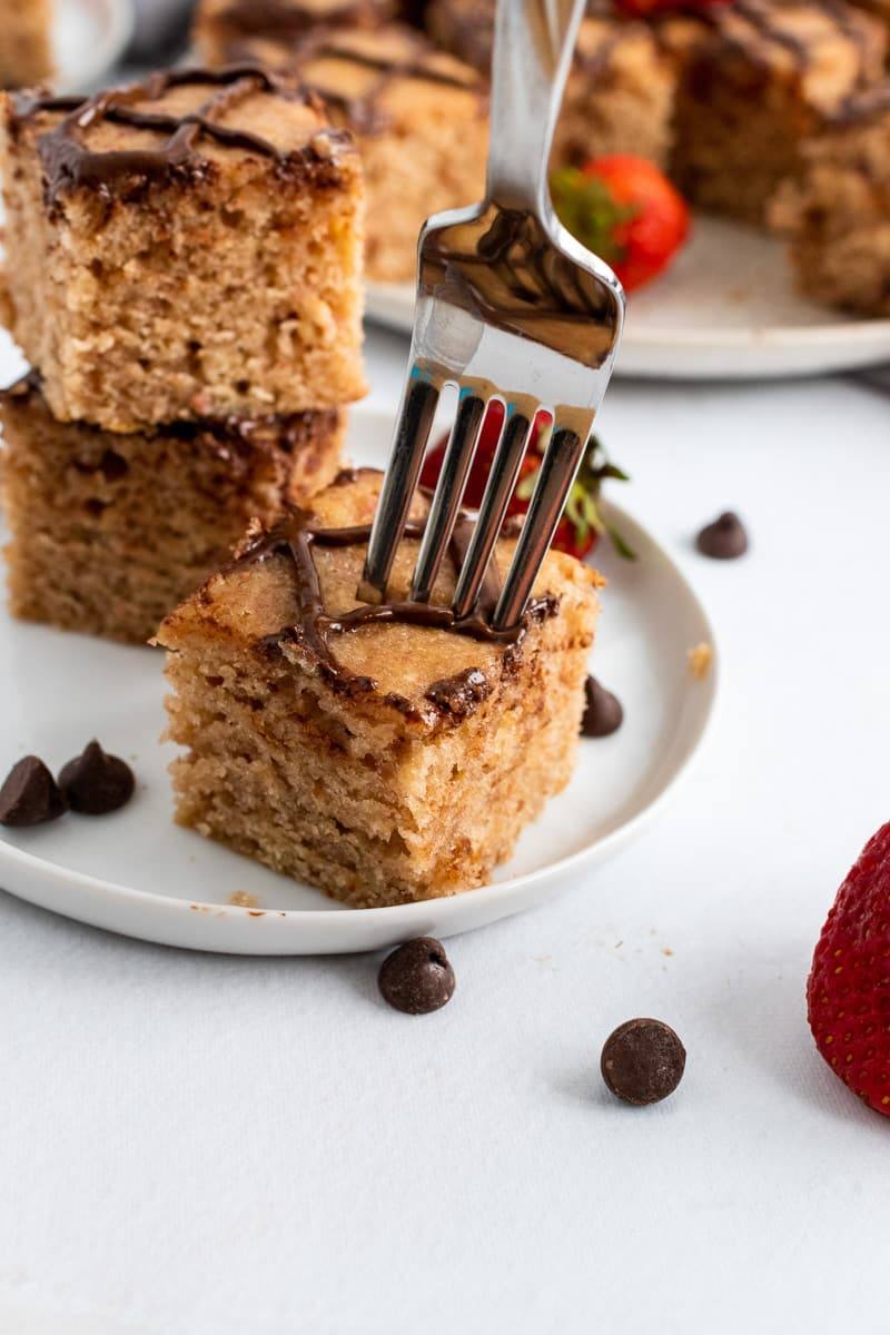 fork digging into strawberry blondies on a white plate