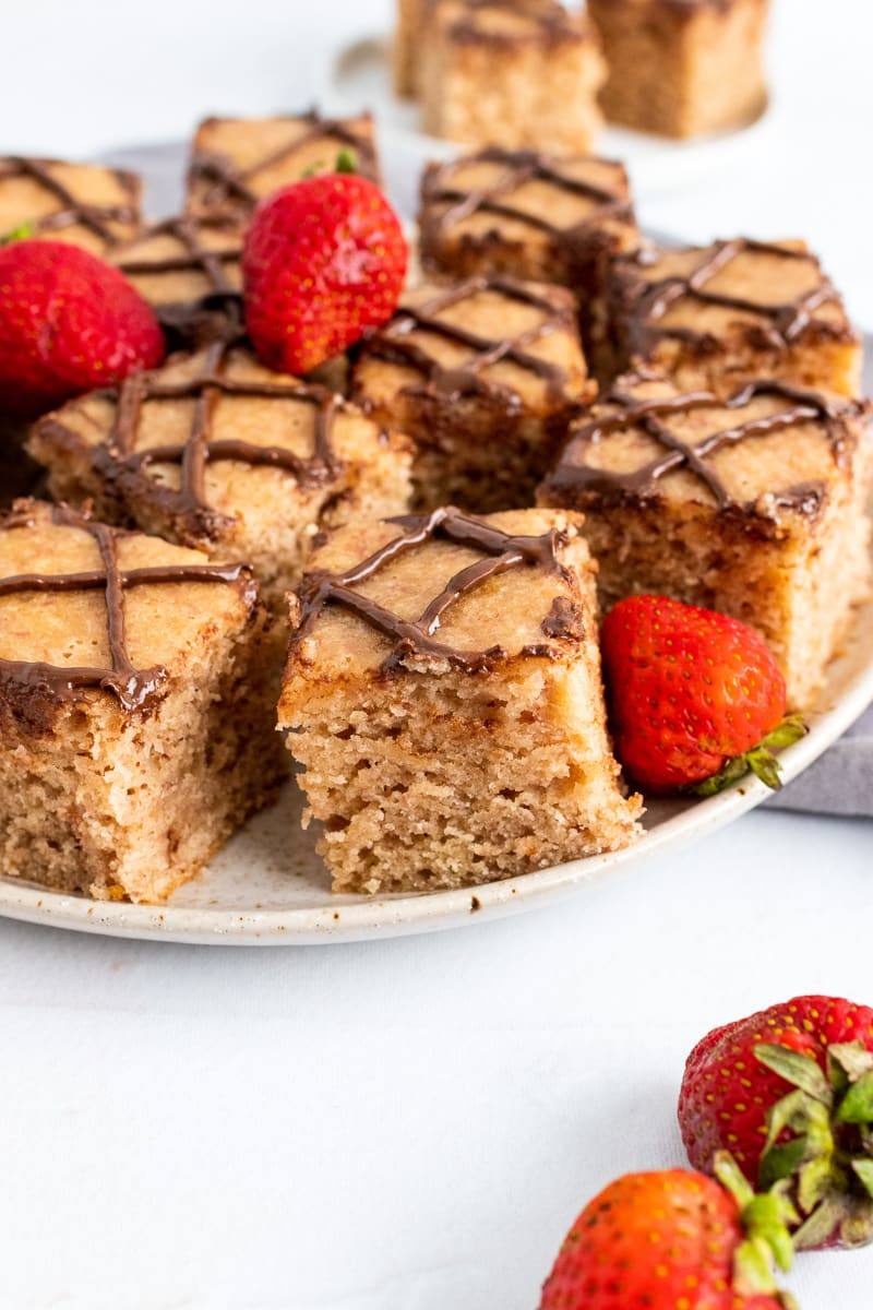 closeup of strawberry blondies on a white serving plate with fresh strawberries
