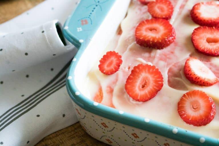 in-progress view of the strawberry poke cake with the cheesecake pudding and sliced fresh strawberries added on top