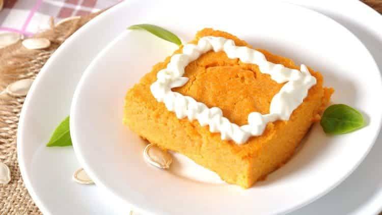 Square of low-fat crustless pumpkin pie with whipped topping on a white plate with pumpkin seeds