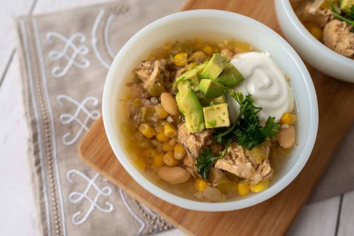 slow cooker white chicken chili being served with avocado and sour cream on top, Image: Dreamstime