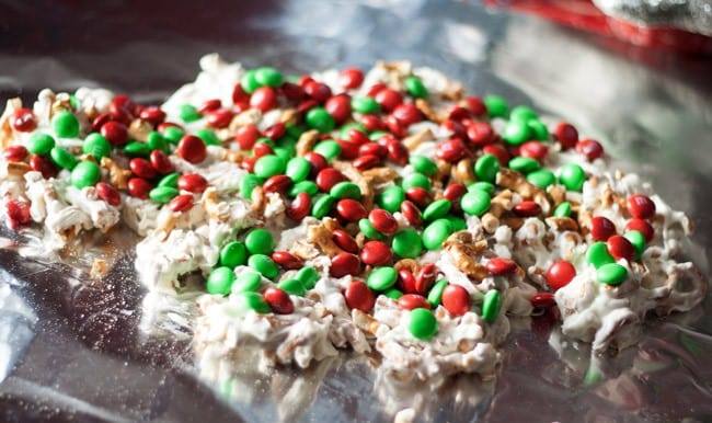 White chocolate and crushed pretzels topped with red and green M&Ms setting on foil