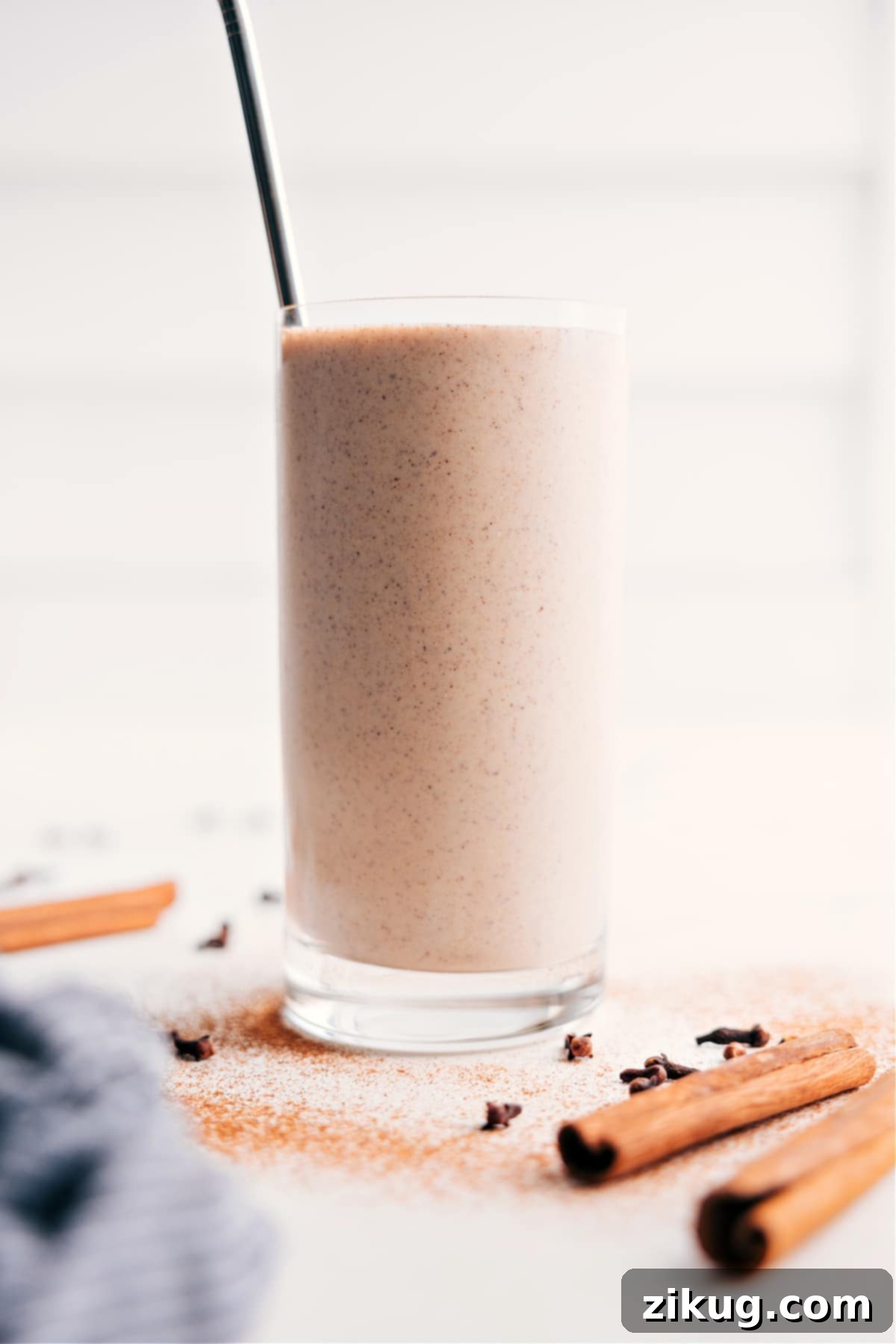 A tall glass filled with a creamy, brown chai smoothie, garnished with a light dusting of cinnamon, invitingly ready to be enjoyed.