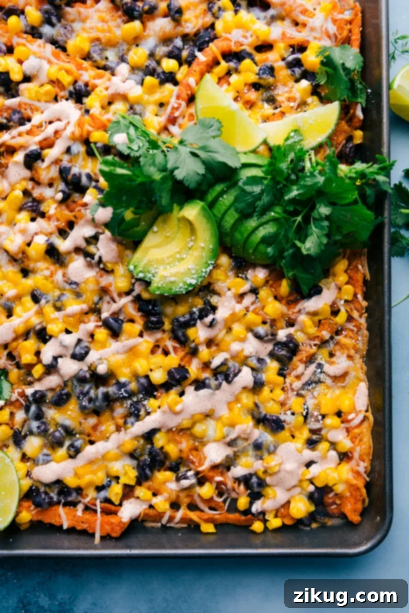 Delicious Sweet Potato Nachos featuring seasoned and roasted sweet potato fries as the base, piled high with crisp corn, savory black beans, and plenty of gooey cheese. Baked to golden perfection, then drizzled with the best chili-lime sauce and topped with fresh avocado and cilantro. A perfect, easy, and quick dinner or appetizer for any occasion. Crispy Sweet Potato Nachos loaded with melted cheese, black beans, and corn, fresh out of the oven, ready to be topped with avocado and chili-lime sauce.