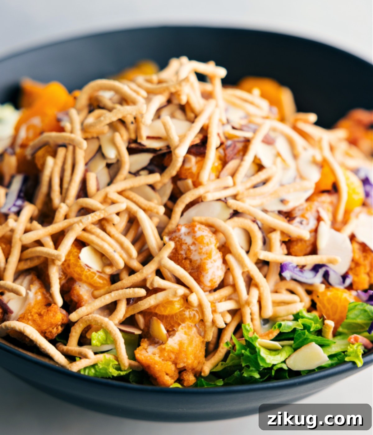 Assembling Applebee's Chicken Salad In A Bowl The crispy Applebee's Chicken Salad, featuring visible chow mein noodles and other vibrant ingredients, thoroughly tossed in a large mixing bowl.