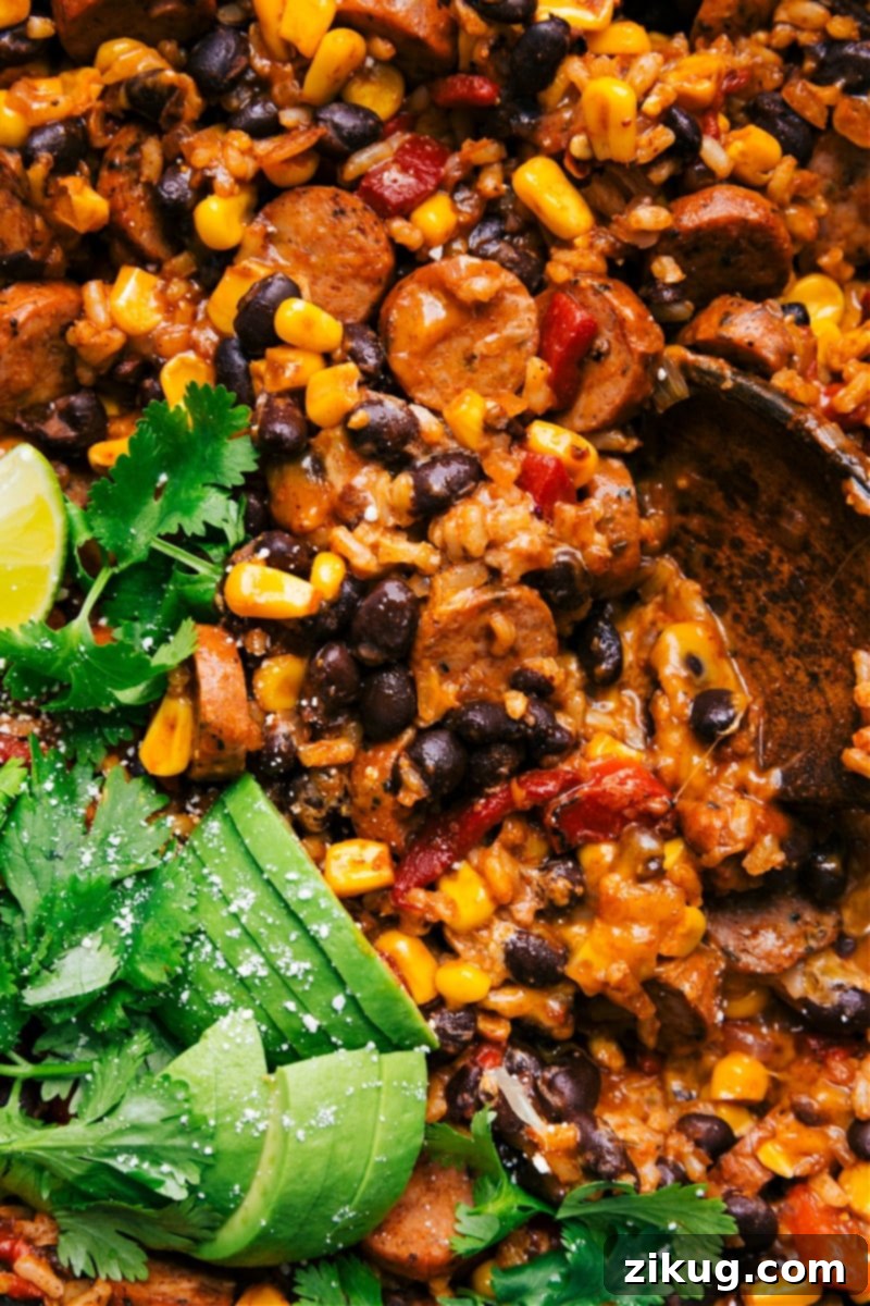 One-Skillet Sausage and Rice: A Flavorful and Quick Dinner Solution Delicious one-skillet sausage and rice with smoked chicken sausage, sweet corn, black beans, and roasted peppers, garnished with fresh cilantro and lime.