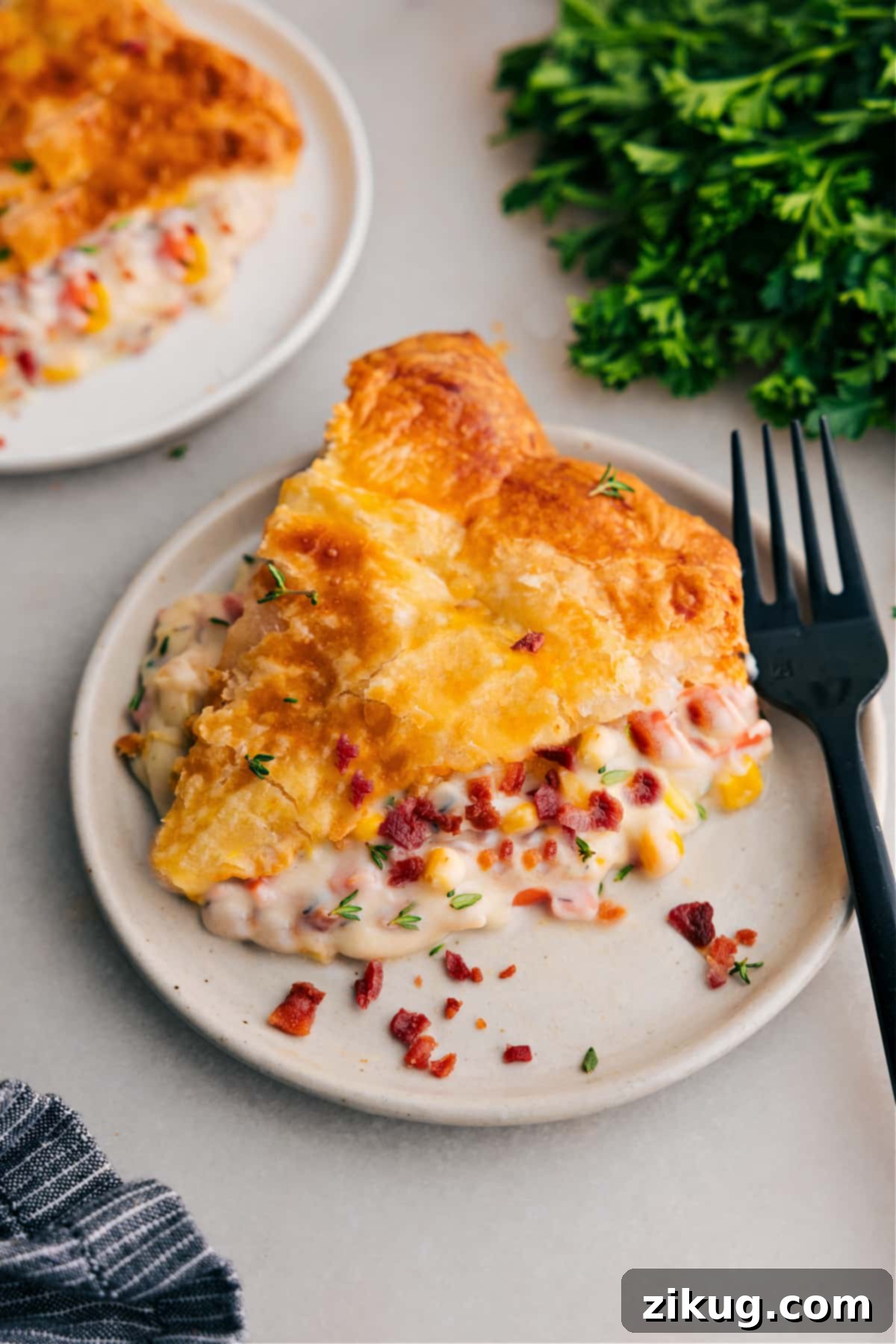 This Corn Chowder Pot Pie channels all the best parts of chicken corn chowder into an ultra-comforting and delicious pot pie! Sweet corn, crisp bacon, and tender chicken in a cheesy sauce all packaged under flaky puff pastry dough -- what more could you want for a comfort-meal type dinner?! Recipe via ChelseasMessyApron #dinner #quick #easy #simple #best #comfortfood #familydinner #kidfriendly #corn #chowder #potpie A perfectly baked slice of Corn Chowder Pot Pie on a white plate, showcasing its golden crust and creamy filling, ready to be enjoyed.