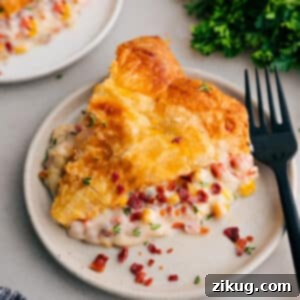 A vibrant close-up of a Corn Chowder Pot Pie, golden and flaky, showing the rich, creamy filling beneath the crust.