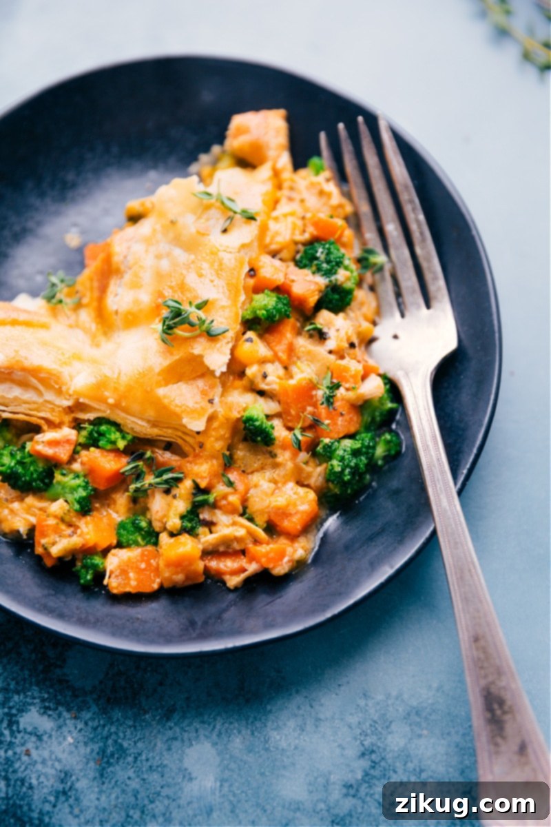 Up close overhead image of a slice of Broccoli Cheddar Pot Pie on a plate, garnished with fresh thyme