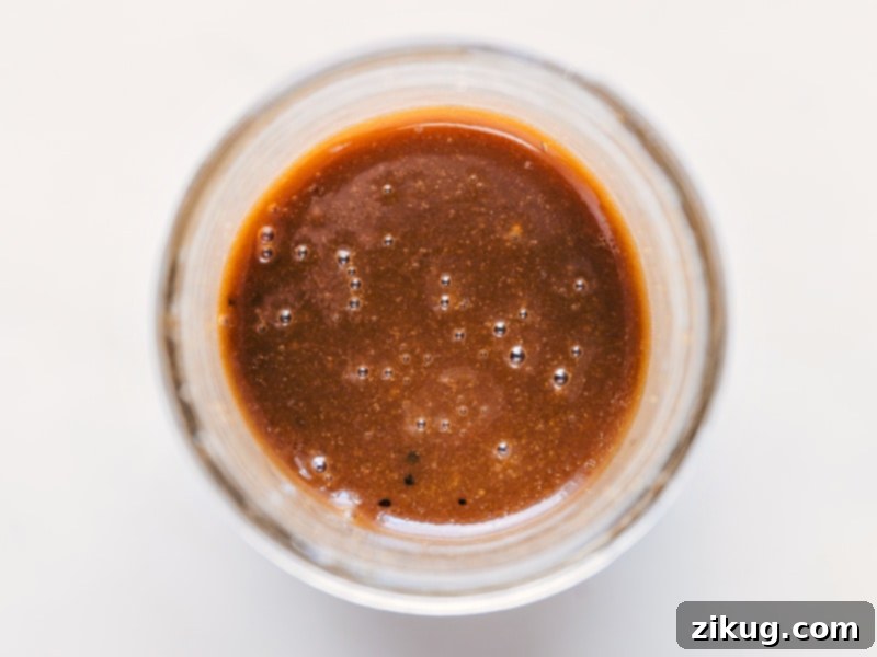 This delicious homemade Balsamic Vinaigrette is ready in minutes, requiring no special kitchen tools! It boasts balanced, tangy flavors and a perfect thickness for salads and roasted vegetables. Recipe via ChelseasMessyApron #salad #saladdressing #clean #healthy #sidesalad #balsamic #vinaigrette Close-up image of the freshly mixed Balsamic Vinaigrette in a glass jar, showing its emulsified, smooth texture.