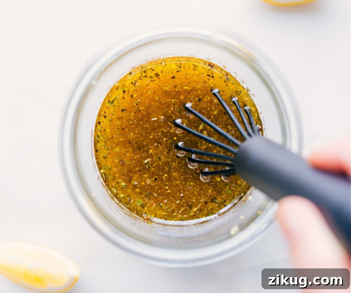How To Make Lemon Vinaigrette A hand vigorously whisking all the ingredients for the homemade Lemon Vinaigrette in a glass bowl.