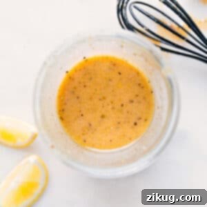 A close-up shot of a glass jar filled with the vibrant, golden Lemon Vinaigrette, ready for use.