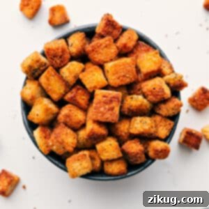 A close-up shot of golden-brown homemade croutons in a white bowl.