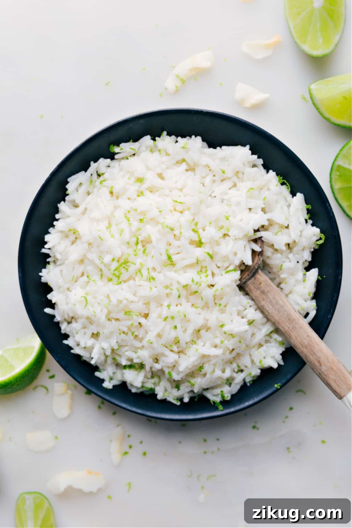 The Best Coconut Rice Recipe A beautifully presented bowl of creamy Coconut Rice, garnished with vibrant fresh lime zest and a wedge of lime, ready to be served. The texture of the rice is fluffy and inviting, highlighting the rich coconut flavor and refreshing citrus notes.