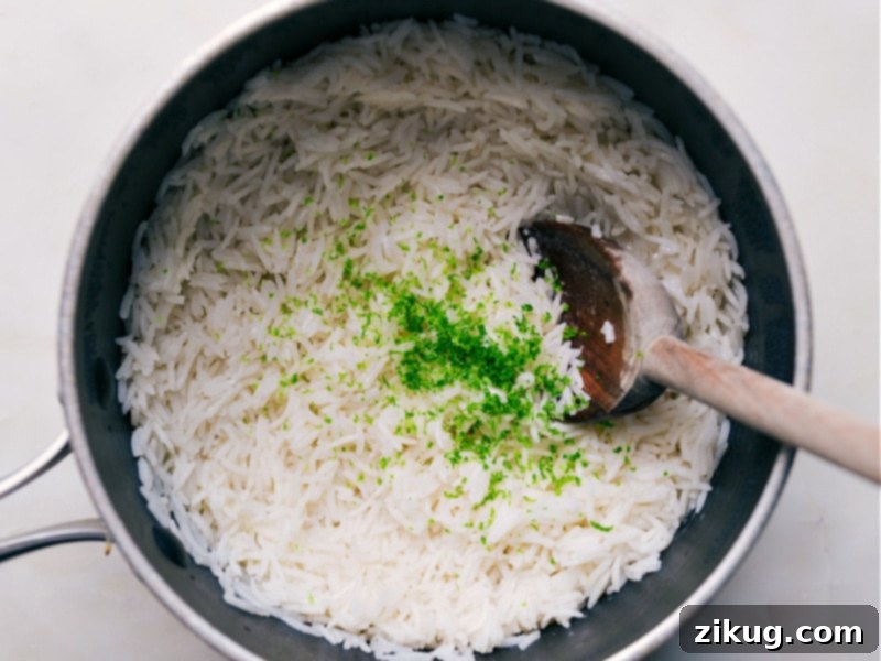 Lime And Coconut Rice Recipe A close-up shot of a hand adding fresh green lime zest and juice to a bowl of perfectly cooked, fluffy coconut rice. The steam rising suggests the rice is still warm, and the vibrant colors indicate fresh ingredients.