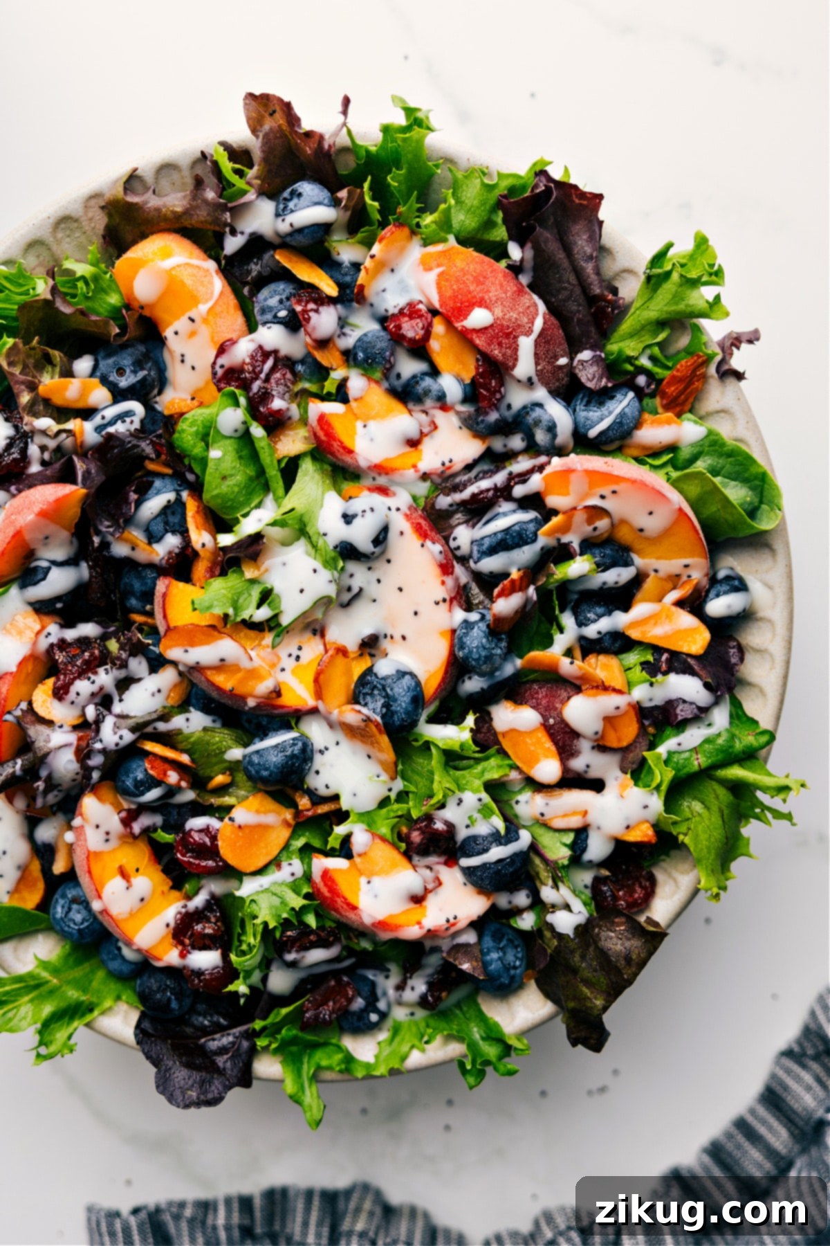 Simple And Delicious Poppyseed Dressing Recipe A vibrant bowl of peach and blueberry salad, generously drizzled with this luscious homemade poppyseed dressing recipe.