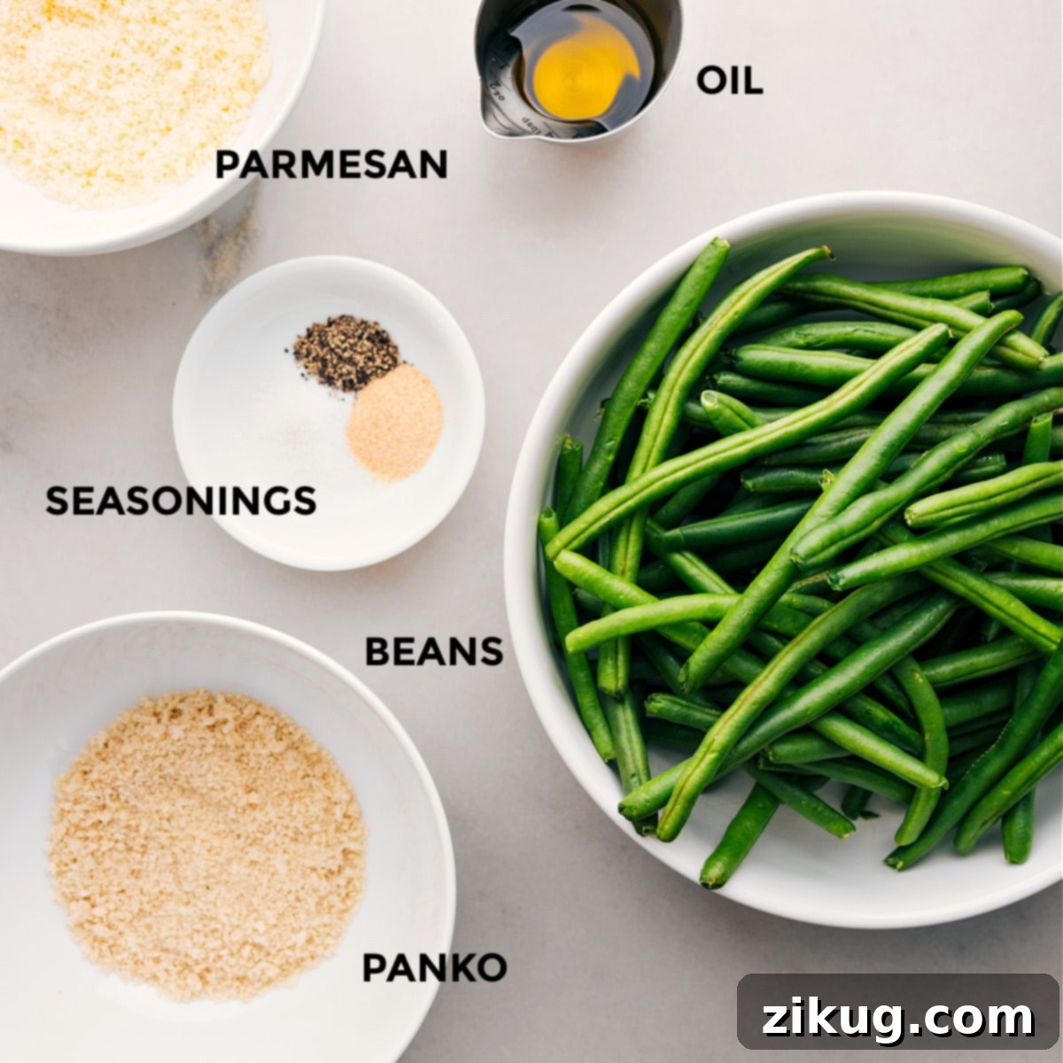 Ingredients In Roasted Green Beans (Two Ways) Ingredients for roasted green beans, including fresh beans, panko breadcrumbs, seasonings, olive oil, and Parmesan cheese, all prepped and ready.