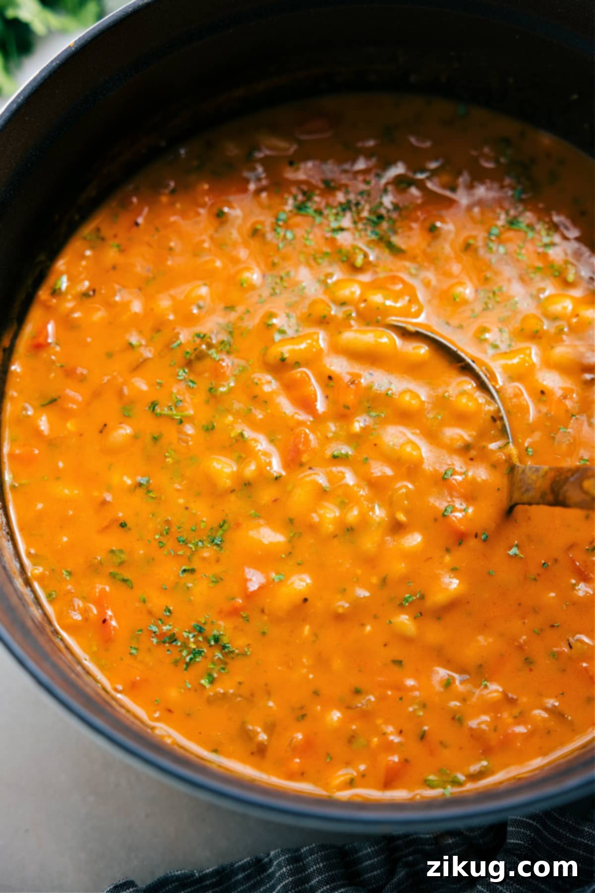 A pot of creamy White Bean Soup, rich with vegetables and ready to be served, is simmering on a stovetop.