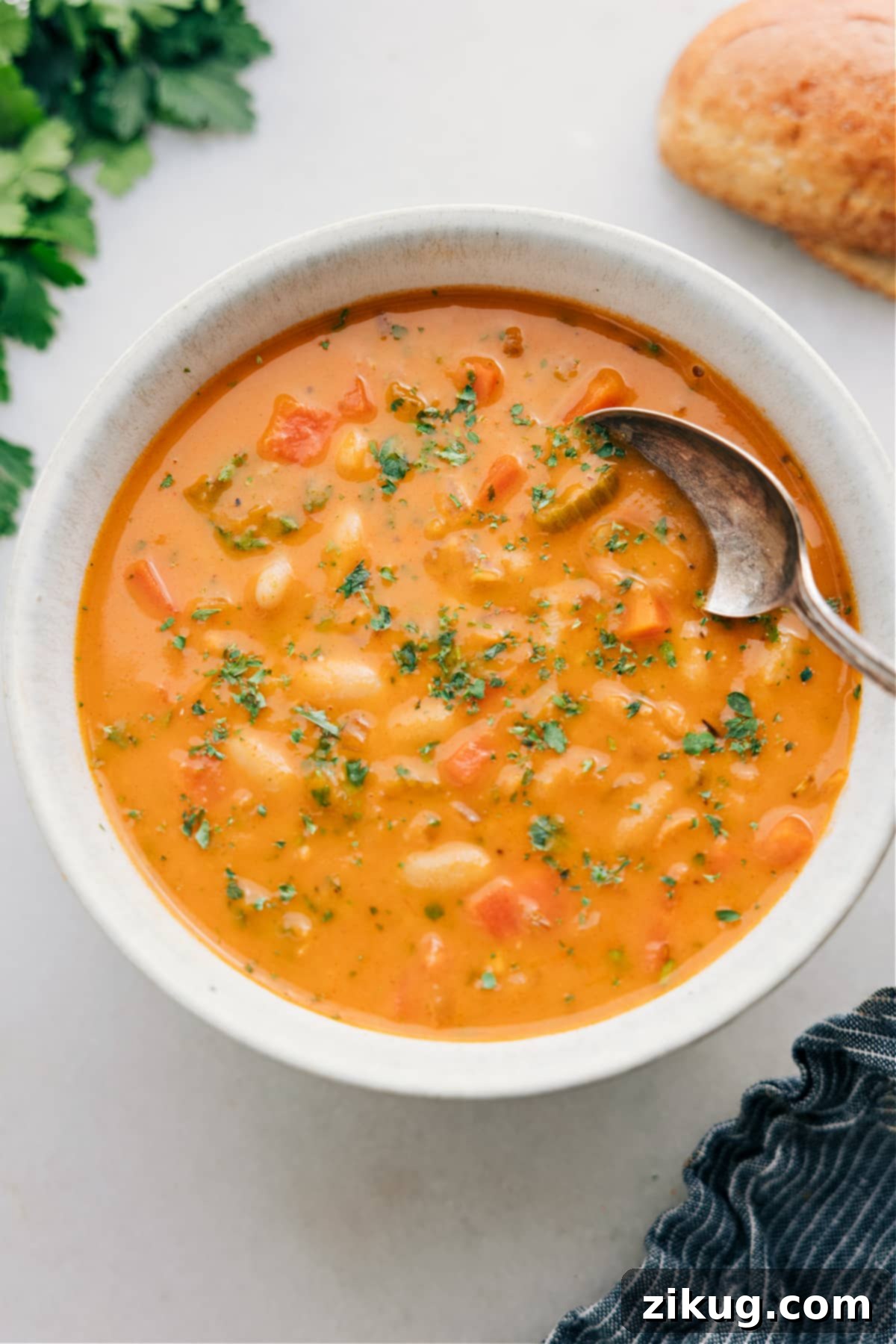 A beautifully served bowl of creamy White Bean Soup, garnished with fresh herbs and a drizzle of pesto, ready to be enjoyed.