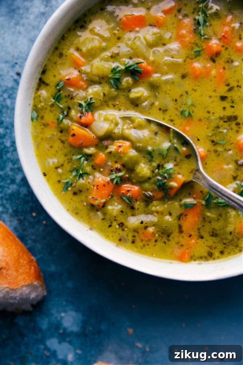Up-close overhead image of a rich, creamy bowl of Vegetarian Split Pea Soup with a spoon lifting out a spoonful, showing its thick texture.