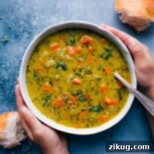 A bowl of creamy Vegetarian Split Pea Soup with a spoon in it, garnished with fresh herbs.