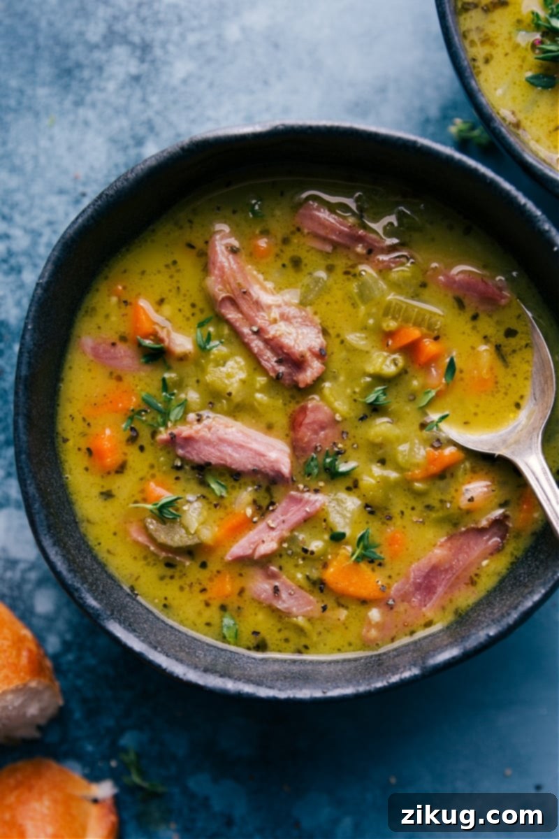 Hearty Split Pea Soup with Ham for Serving An overhead view of a bowl of comforting Split Pea Soup with ham, garnished with a sprig of fresh thyme, served alongside a slice of crusty bread.