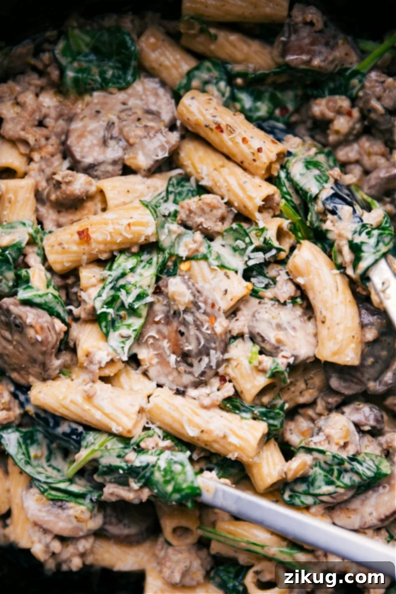 Delicious Creamy Sausage and Mushroom Rigatoni pasta dish A large pot filled with creamy sausage and mushroom rigatoni, ready to be served. The pasta is coated in a rich, savory sauce, topped with fresh herbs.
