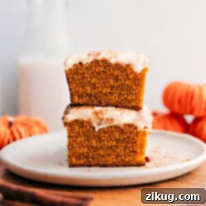 Close-up of a frosted pumpkin bar, showing its moist texture and creamy topping.