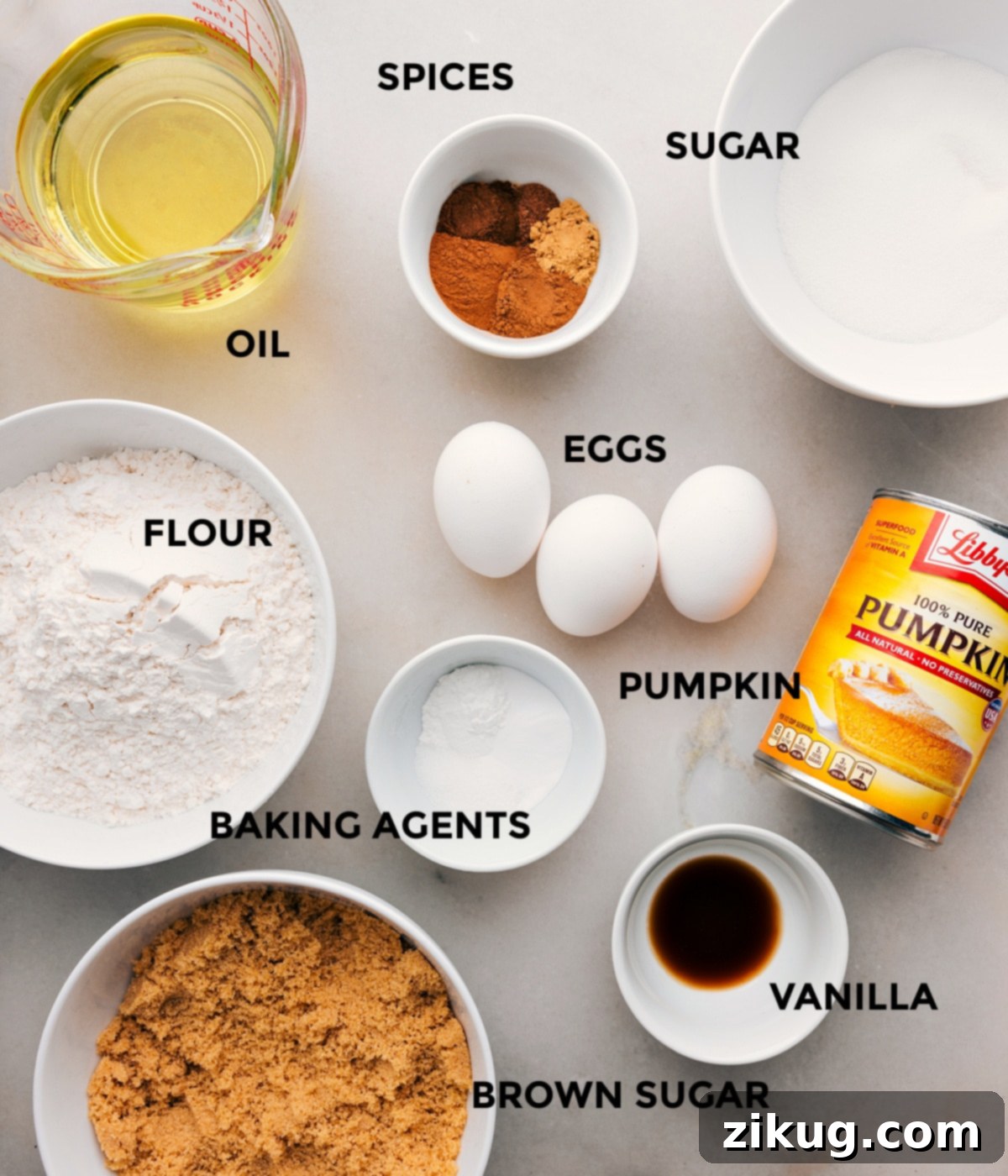 All the prepped ingredients for pumpkin bars including pumpkin puree, spices, sugars, flour, eggs, and oils.