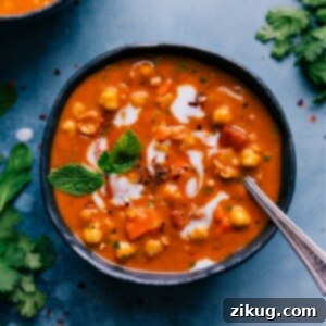 A bowl of Chickpea Soup with fresh cilantro and a lemon wedge.