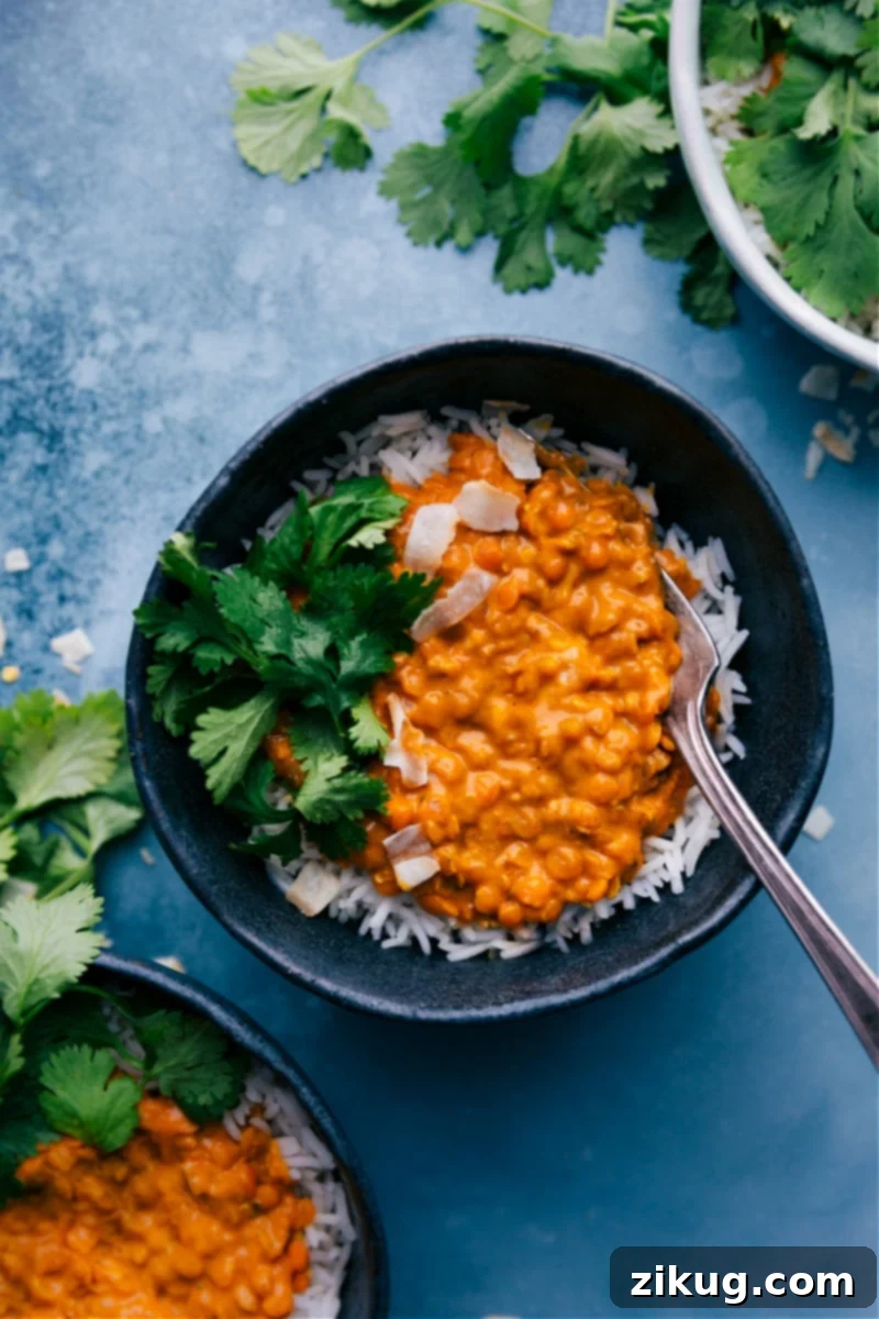 A vibrant bowl of homemade Daal, garnished with fresh cilantro, ready to be enjoyed. The rich orange color of the lentils stands out.