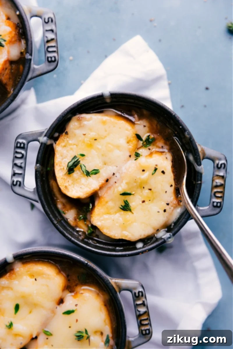 This French Onion Soup combines perfectly caramelized onions in a rich broth. The soup gets topped with croutons that have been topped with melted cheese. Recipe via ChelseasMessyApron #dinner #quick #easy #soup #best #appetizer #bread #French #onion #soup Overhead image of the French Onion Soup