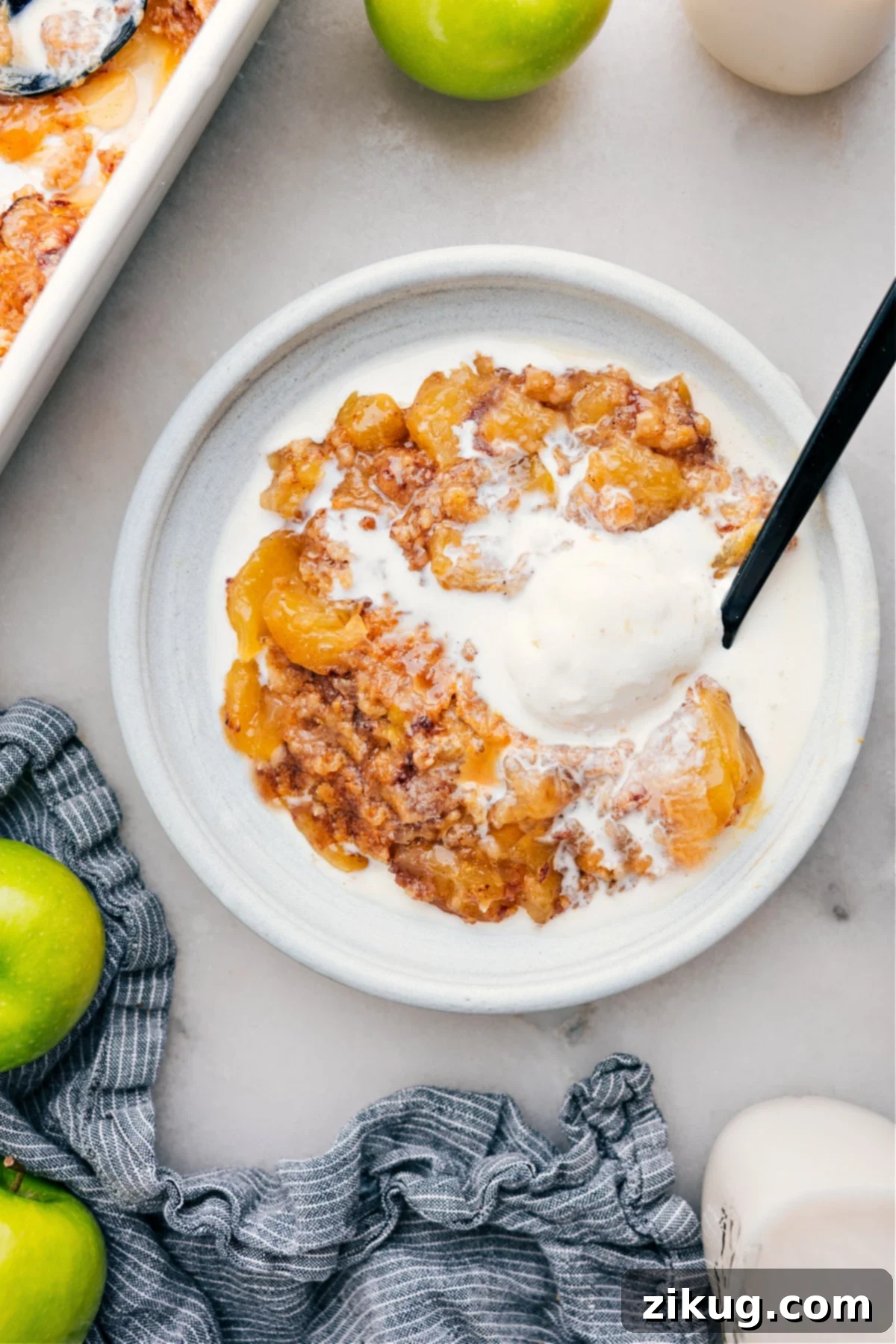 The Best Apple Dump Cake With Ice Cream Apple Dump Cake on a plate with ice cream, showcasing its gooey texture.