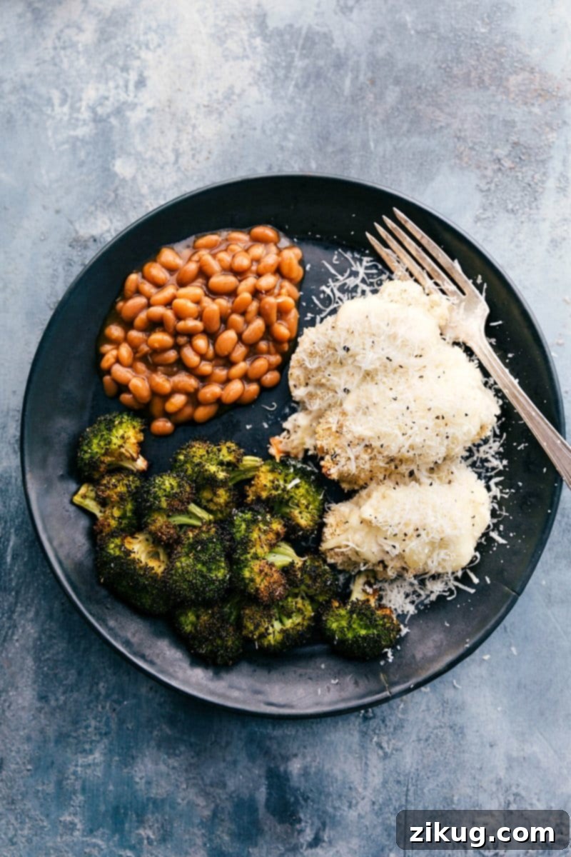 Delicious Baked Alfredo Chicken with Sides of Beans and Baked Broccoli for a Perfect Meal Golden-brown baked alfredo chicken breasts, generously coated in creamy sauce and melted cheese, served alongside tender roasted broccoli and rich baked beans on a rustic plate, ready to be enjoyed.
