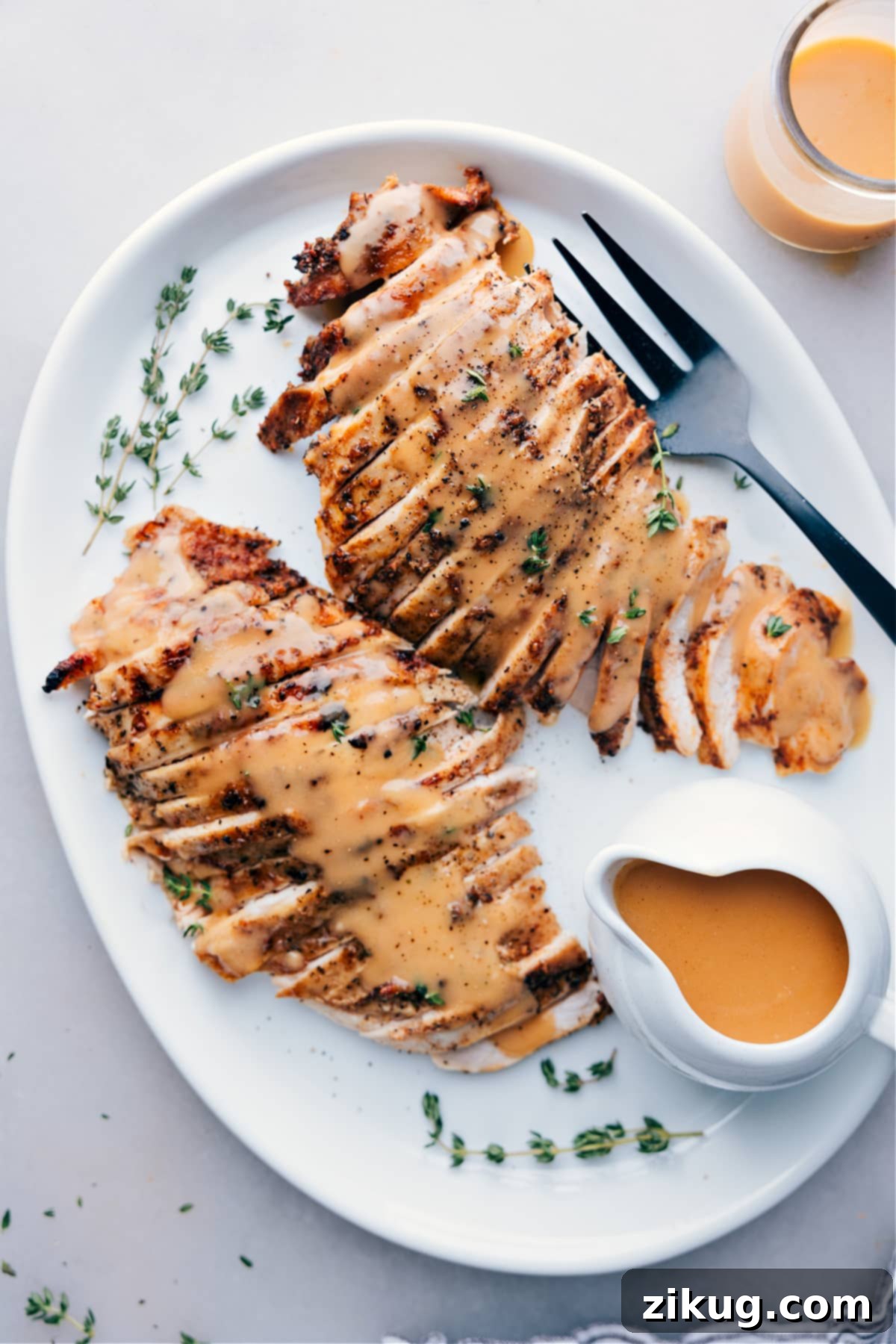 Perfectly sliced, moist turkey breast cooked in a crockpot, served elegantly on a plate, generously topped with savory gravy and garnished with fresh herbs, ready to be enjoyed.