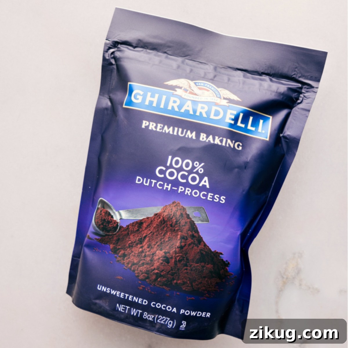 A close-up of high-quality Dutch-process cocoa powder, highlighting its fine texture and deep color, essential for rich hot fudge sauce.