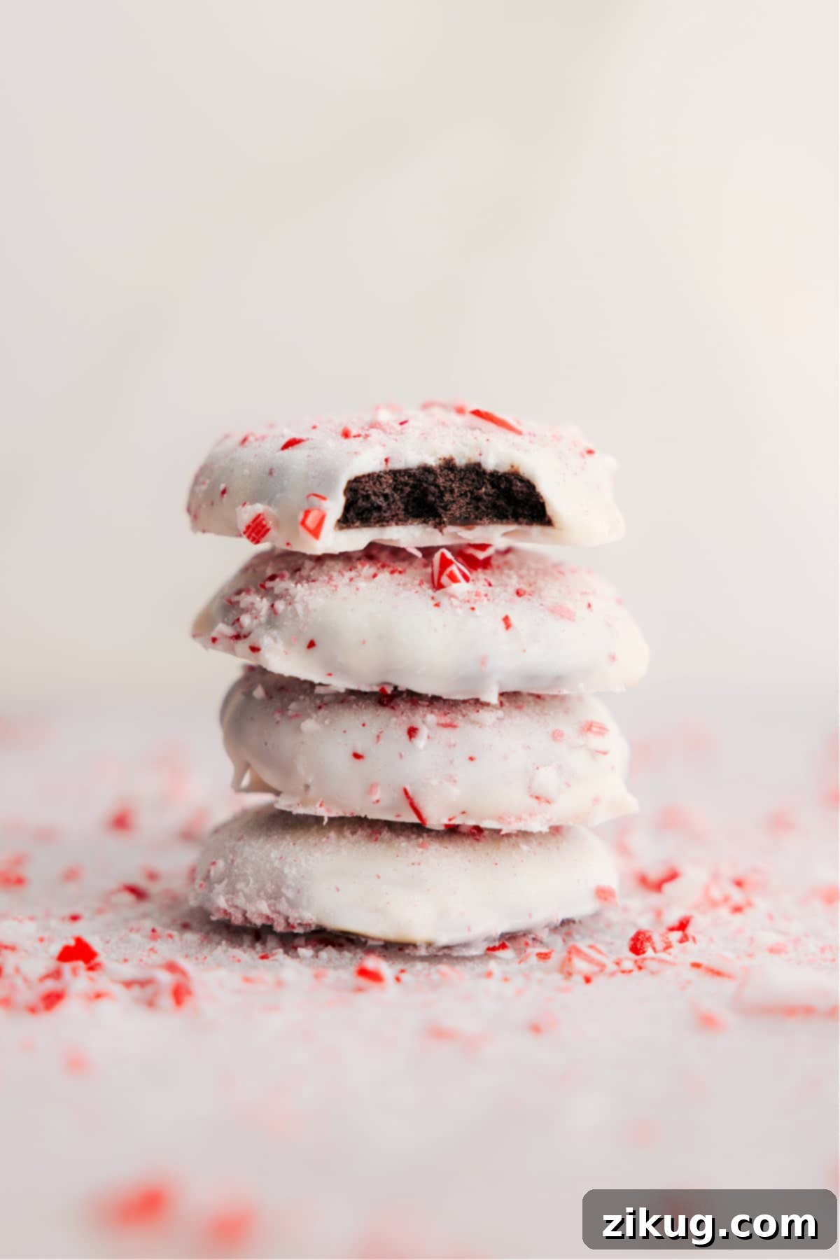 Stacked Peppermint Cookies with a bite missing from one, showcasing the minty green interior and festive white chocolate coating with crushed candy canes.