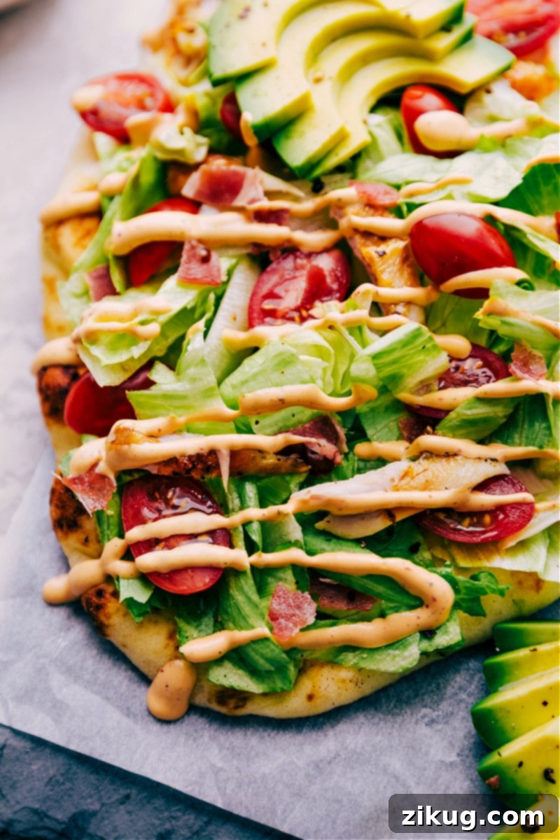 Fully Topped Chipotle Chicken Flatbread A whole Chipotle Chicken Flatbread with all its toppings and dressing, ready to be sliced.