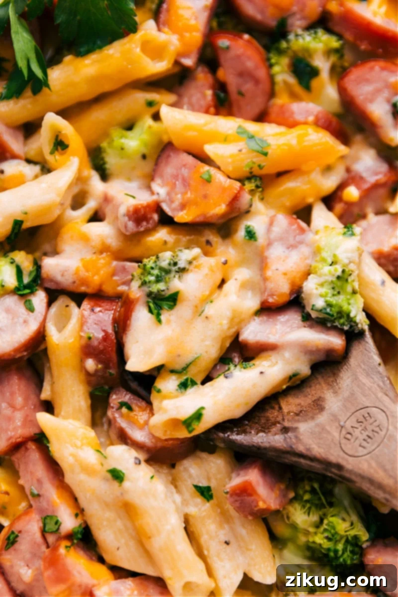 This simple Cheesy Sausage Pasta is all made in ONE baking dish -- the oven does all the work! No need to pre-boil the pasta or pre-cook the sausage, just dump it all in and bake. Recipe via ChelseasMessyApron #dinner #quick #easy #simple #best #onepan #creamy #cheesy #sausage #pasta Overhead image of the perfectly baked, golden brown Cheesy Sausage Pasta, fresh out of the oven, garnished with fresh parsley.