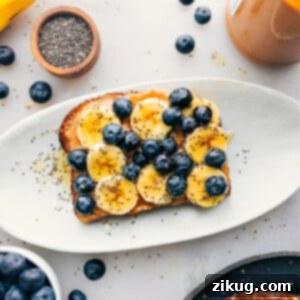 Breakfast toast on a platter with all the fun toppings like bananas, blueberries, chia seeds, and honey.