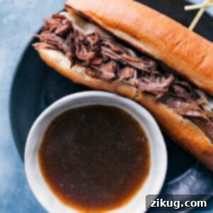 French Dip Sandwich on a cutting board with a small bowl of au jus for dipping.