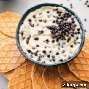 The best Cannoli Dip in a bowl with waffle crackers ready to be dipped in.