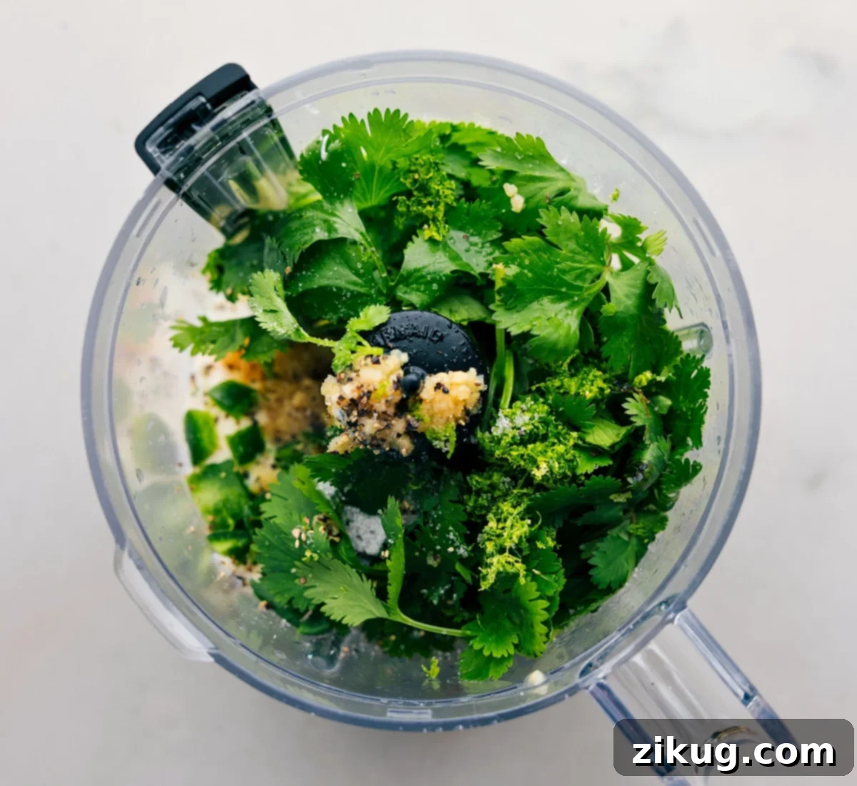 All ingredients for the cilantro lime sauce being carefully added into a food processor for blending.
