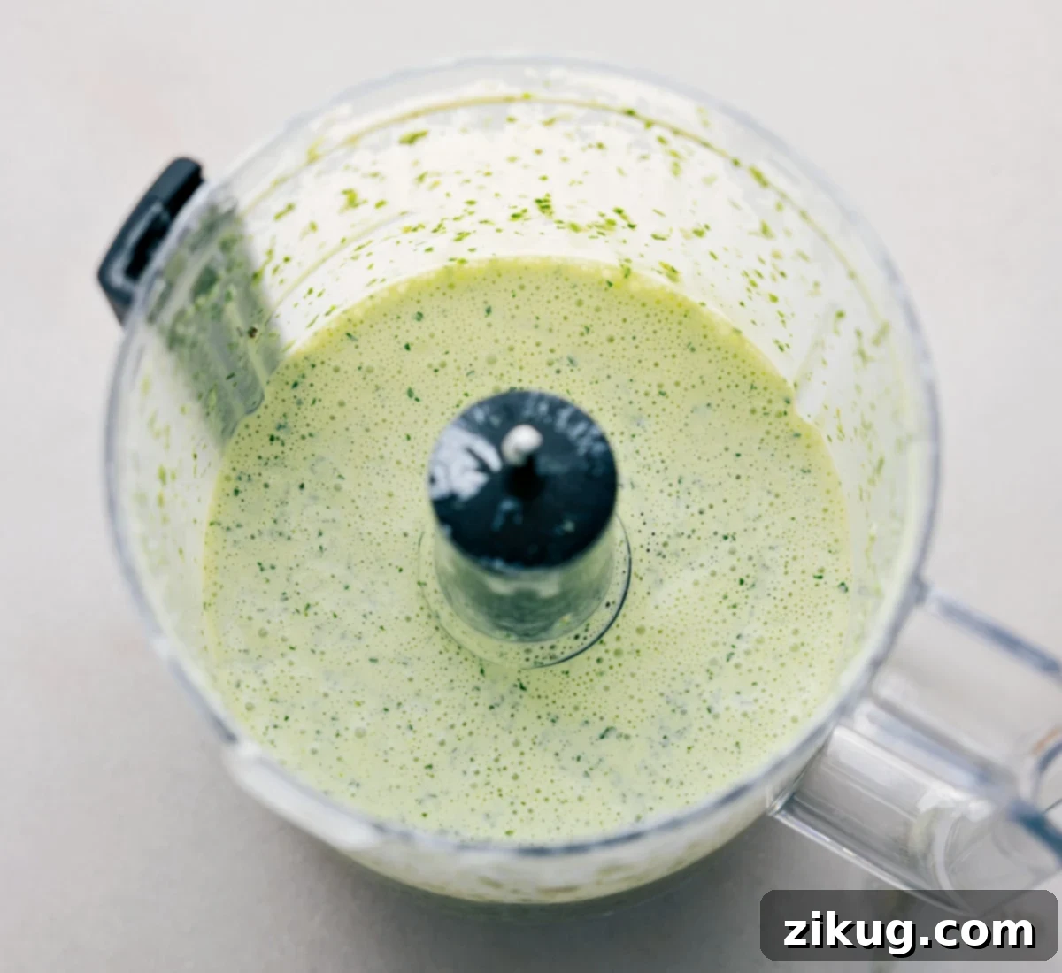 Close-up shot of the vibrant cilantro lime sauce being blended in a food processor, creating a smooth, creamy texture.