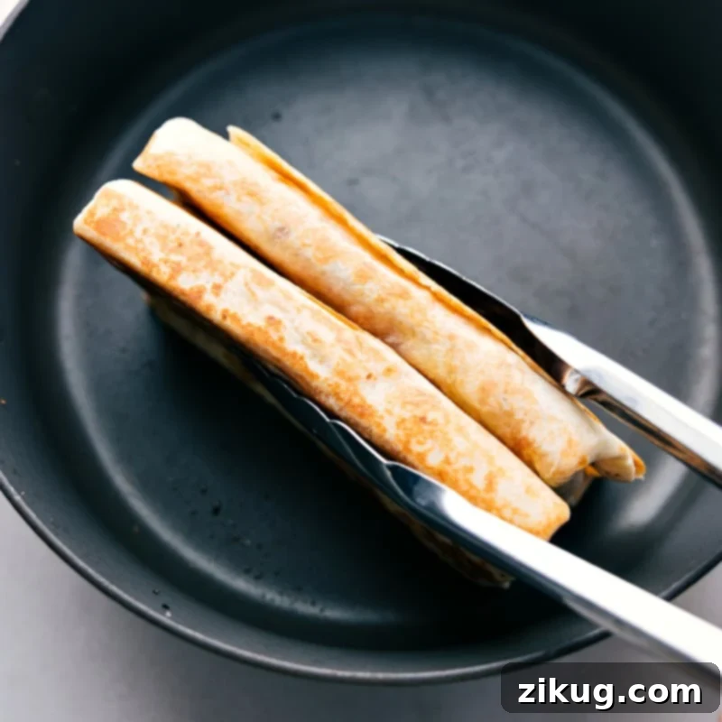 The final step: perfectly crisped BBQ Chicken Wraps are taken off the skillet. Crispy BBQ Chicken Wraps being carefully removed from a hot skillet with tongs, ready to be served.