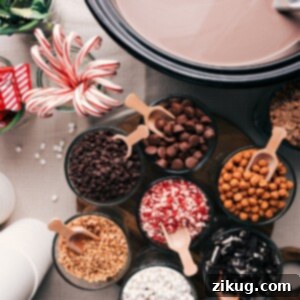 Gourmet Hot Chocolate Bar 2 Assorted hot chocolate ingredients and toppings displayed on a table, including cups, chocolate shavings, whipped cream, and marshmallows.