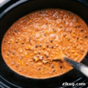 A bowl of creamy slow cooker chicken chili with various toppings, seen from above.