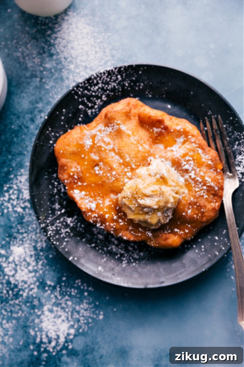 Overhead image of a beautifully prepared Utah Scone ready to be served, topped with honey and powdered sugar